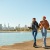 two people walking near the beach near a city