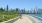 a couple riding bikes on a path with a city skyline in the background