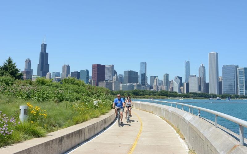 Settle into comfort at The Edison a couple riding bikes on a path with a city skyline in the background